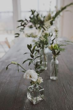 three vases with flowers are sitting on a table