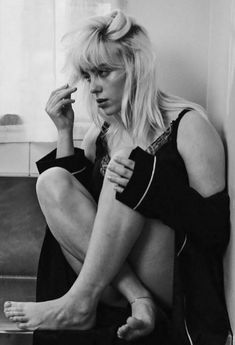 a black and white photo of a woman sitting on a counter with her legs crossed