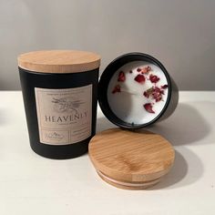 a candle with flowers in it sitting next to a wooden container on a white surface