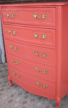 an orange dresser with gold handles and drawers on carpeted floor next to brick wall