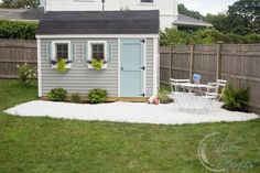 a small backyard with a shed, table and chairs