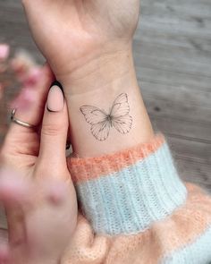 a woman's wrist with a small butterfly tattoo on the left side of her arm