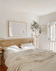 a bed with white sheets and pillows in a bedroom