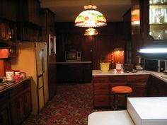 a kitchen with wooden cabinets and an island in the middle is lit by a stained glass light