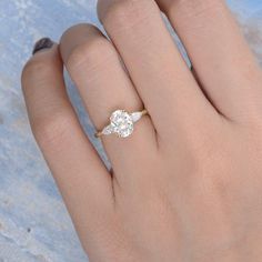 a woman's hand with a diamond ring on top of her finger and the other hand holding an engagement ring