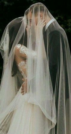 a bride and groom kissing under a veil