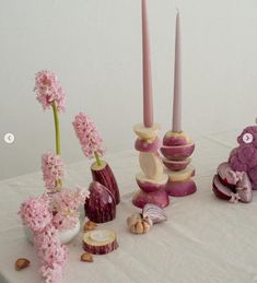 a table topped with vases filled with pink flowers and small candles next to each other