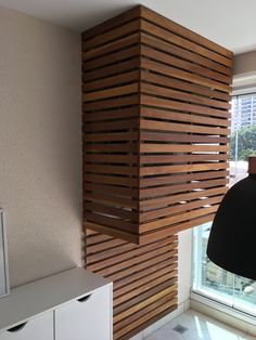 a lamp hanging from the side of a wall next to a window with wooden slats on it