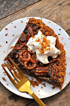 a piece of pecan pie on a white plate with a fork and whipped cream