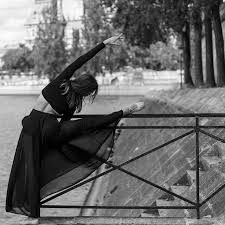 a woman sitting on top of a metal rail next to a tree filled park area