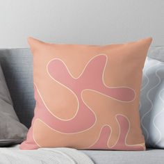 an orange and pink pillow sitting on top of a couch next to a gray throw pillow