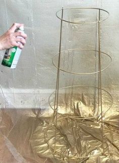 a man is spray painting a metal rack with gold foil on it and another person is holding a spray bottle