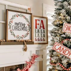 two christmas signs are hung on the mantle next to a decorated christmas tree in front of a window