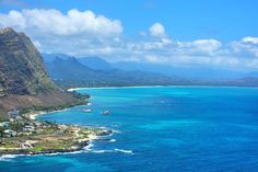 an aerial view of the ocean with mountains in the background