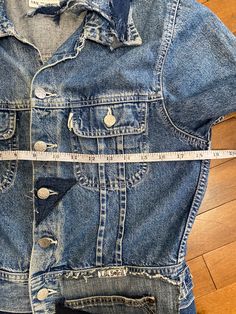 an old jean jacket is being measured with a tape measure on the floor next to it