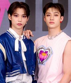 two young men standing next to each other in front of a pink and blue background