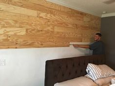 a man standing on top of a bed next to a wooden wall