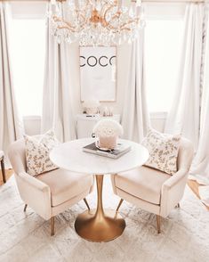 two chairs and a table in a room with chandelier hanging from the ceiling