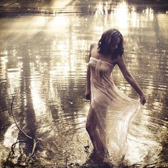 a woman in a white dress standing in the water