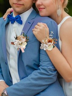 a man in a blue suit and tie hugging a woman with flowers on her lap