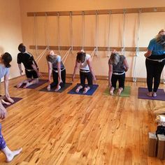 a group of people standing in a room on yoga mats and holding hands behind their backs