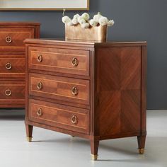 a wooden dresser sitting next to a mirror on top of a table with flowers in it