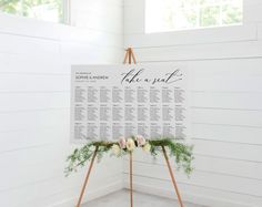 a seating chart on a easel with flowers and greenery