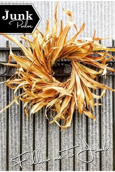 a wreath made out of dried corn sitting on top of a metal grate with the words, fall into the space