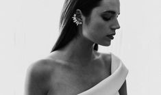 a woman in a white dress is looking down at her cell phone while wearing earrings