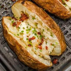 two baked potatoes sitting on top of a pan covered in cheese and toppings with green onions