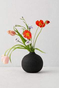 a black vase filled with flowers on top of a table