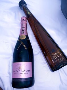 a bottle of champagne next to a wine glass on a white tablecloth covered bed