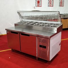 a stainless steel refrigeration unit on red carpeted floor