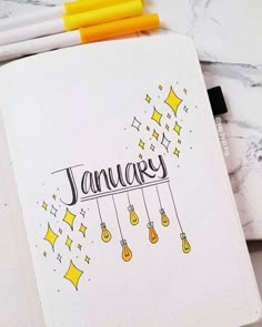 an open notebook with the word january written in cursive writing on it next to some crayons