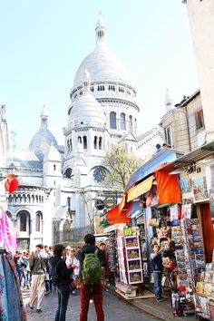 people are walking around in front of an old building with domes on it's roof