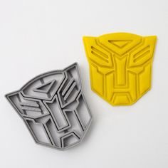 two cookie cutters shaped like the head of a robot and an angry looking mask