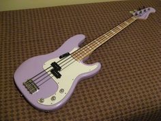 a purple bass guitar sitting on top of a bed