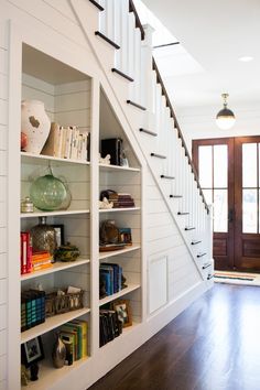 an open book shelf with books on it in the middle of a room next to a staircase