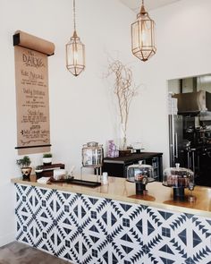 a counter with some food on it and hanging lights in the back ground, behind which is a menu