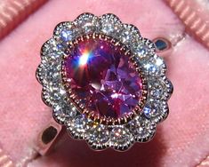 "This is a beautiful and delicate vintage-inspired DAISY ring featuring custom-cut lab gemstone and moissanites, set in milgrained bezels. This ring is custom-made with your choice of center stone, which will be custom-cut for your order. The sample ring is shown with a 7x9mm lab pink sapphire, but you can choose other colored stones in the pull-down menu. Or you can buy this listing as \"mount only\" and add another gemstone or moissanite as the center stone. The custom-cut lab-grown gemstones Filigree Engagement Ring, Daisy Ring, Pink Tourmaline Ring, Pink Or Blue, Antique Pink, Rare Gemstones, Tourmaline Ring, Pink Gemstones, Gold Engagement Ring