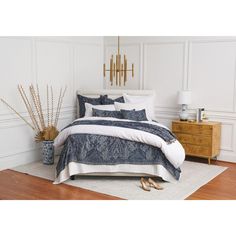 a bedroom with white walls and wooden flooring has a blue comforter on the bed