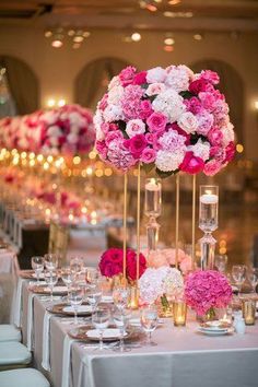 the tables are set up with white linens and pink flowers in tall vases