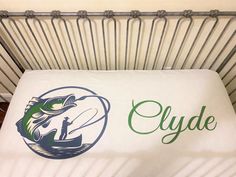 a baby crib with the name clyde on it and a fishing theme in green