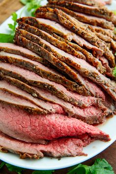 sliced meat on a white plate with lettuce and parsley around the edges