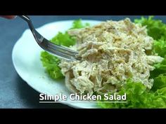 a white plate topped with lettuce covered in chicken salad next to a fork