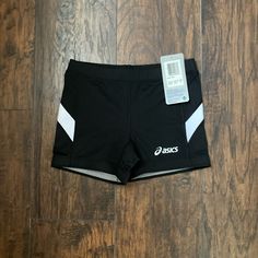 a pair of black shorts sitting on top of a wooden floor next to a tag