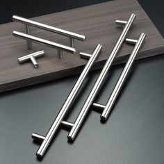 four stainless steel handles on a wooden board and one has three bars attached to it