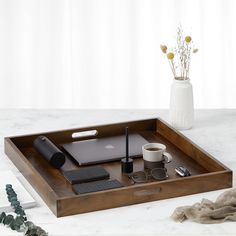 a wooden tray with a laptop, coffee cup and other items on it next to flowers