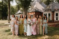 a group of women standing next to each other in front of a house