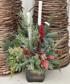 a planter filled with evergreen and red berries next to two large stacks of logs